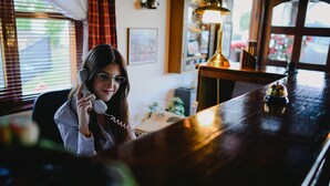 Iemand zit aan een houten toog met een telefoon.