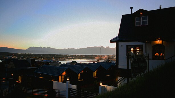 Een hotel aan de kust met uitzicht op zee en bergen.