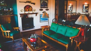 Een gezellige woonkamer met een groene bank, een houten bijzettafeltje en een open haard.