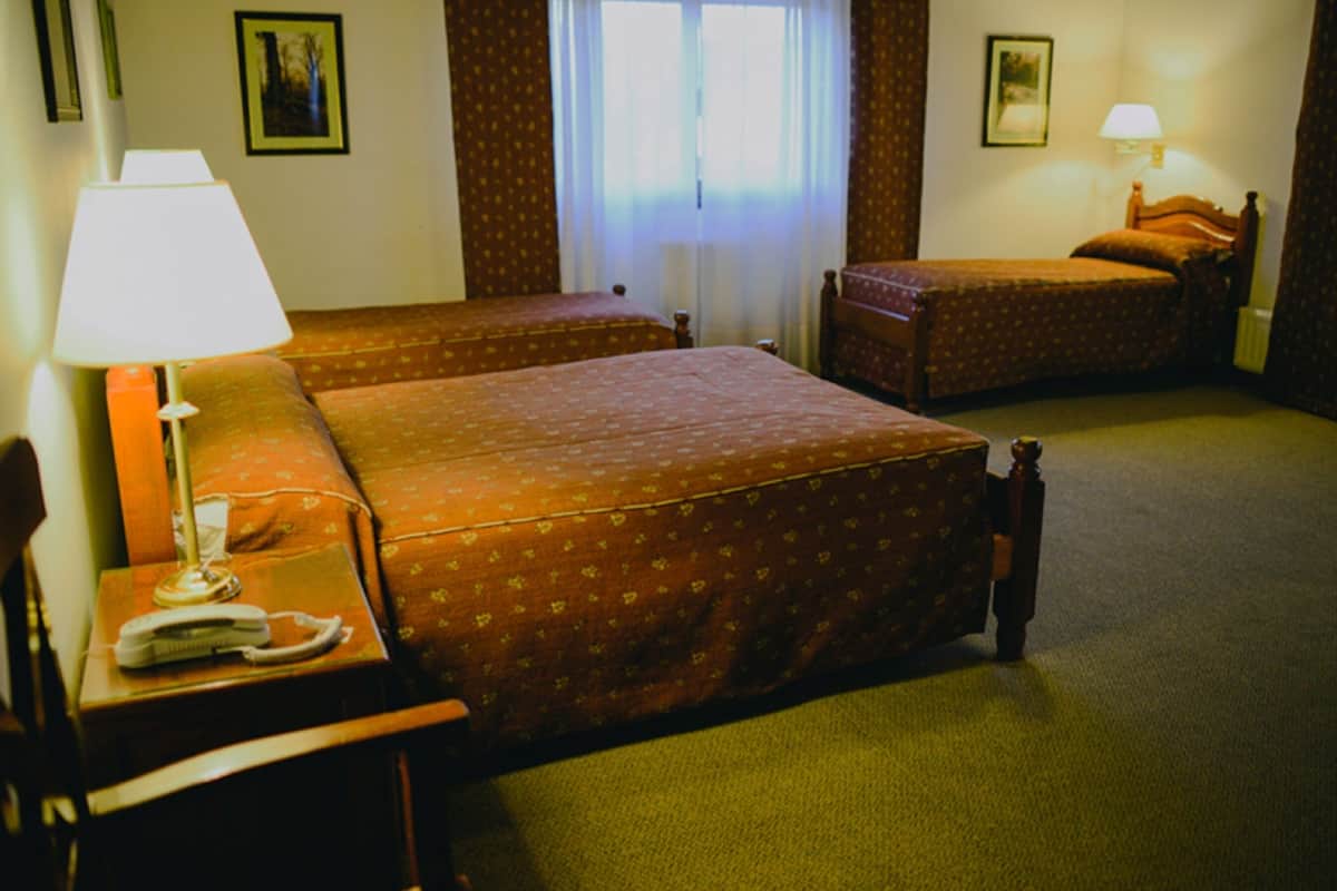 Une chambre d’hôtel avec deux lits, un bureau avec une lampe et un téléphone.