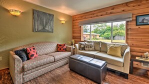 Ein gemütliches Wohnzimmer mit zwei Sofas, einem Couchtisch und einem großen Fenster mit Blick ins Freie.