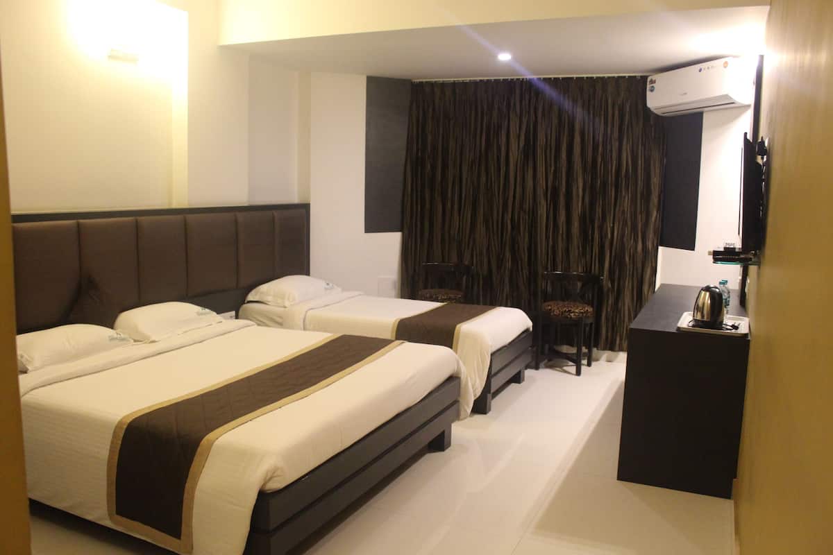 Quarto de hotel com duas camas, uma escrivaninha, uma cadeira, uma cortina e um aparelho de ar condicionado.
