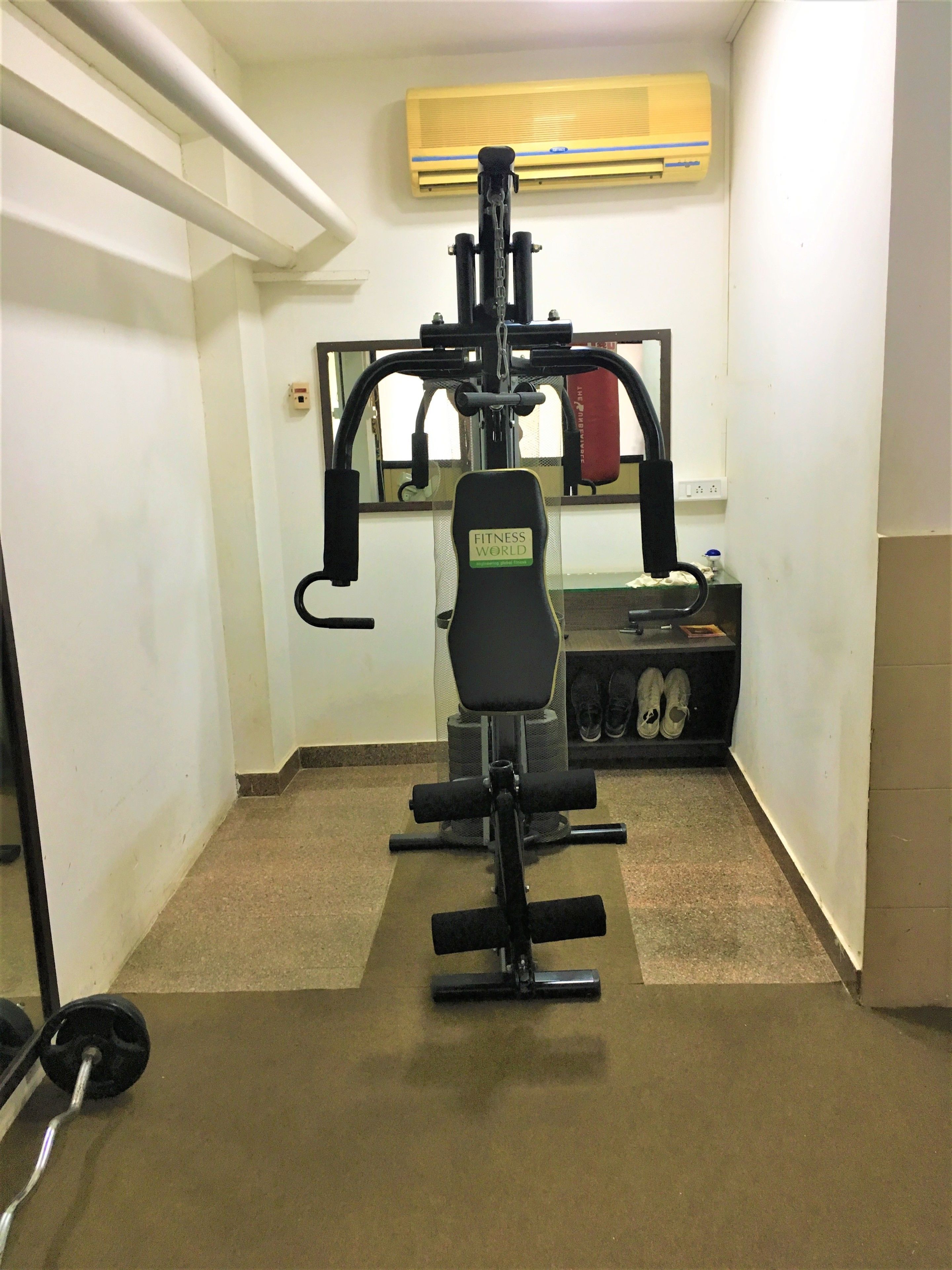 A gym with a bench press, a squat rack, and a mirror on the wall.