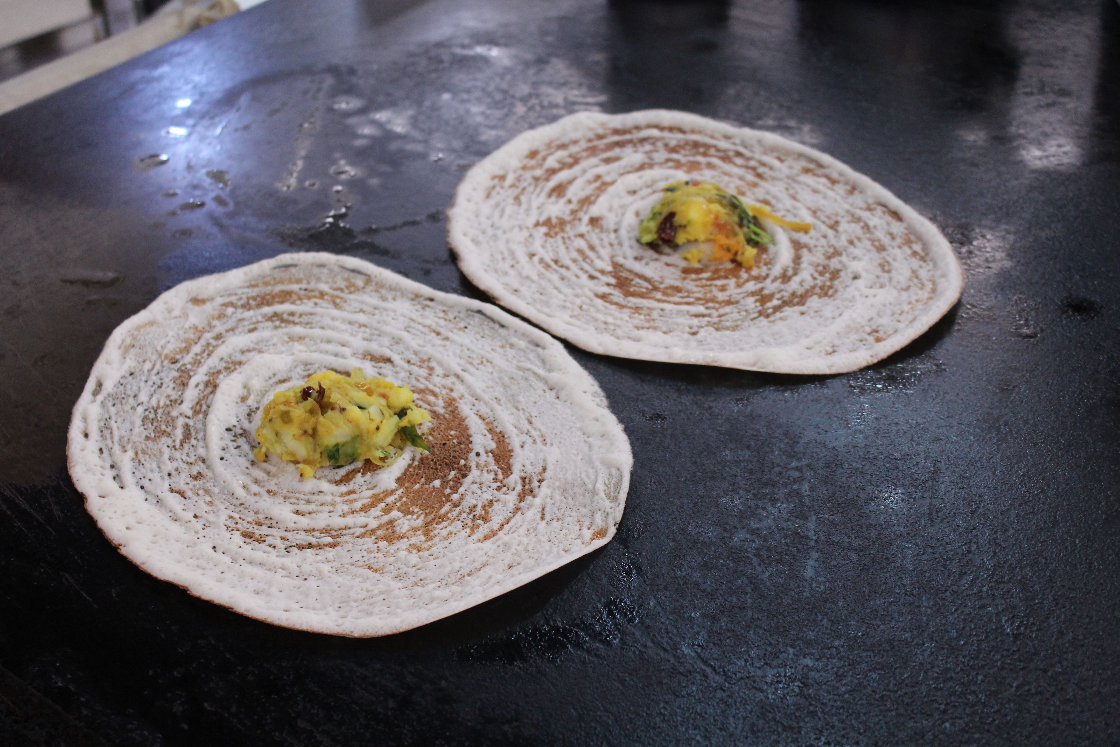 Two flatbreads on a black surface with a circular pattern.