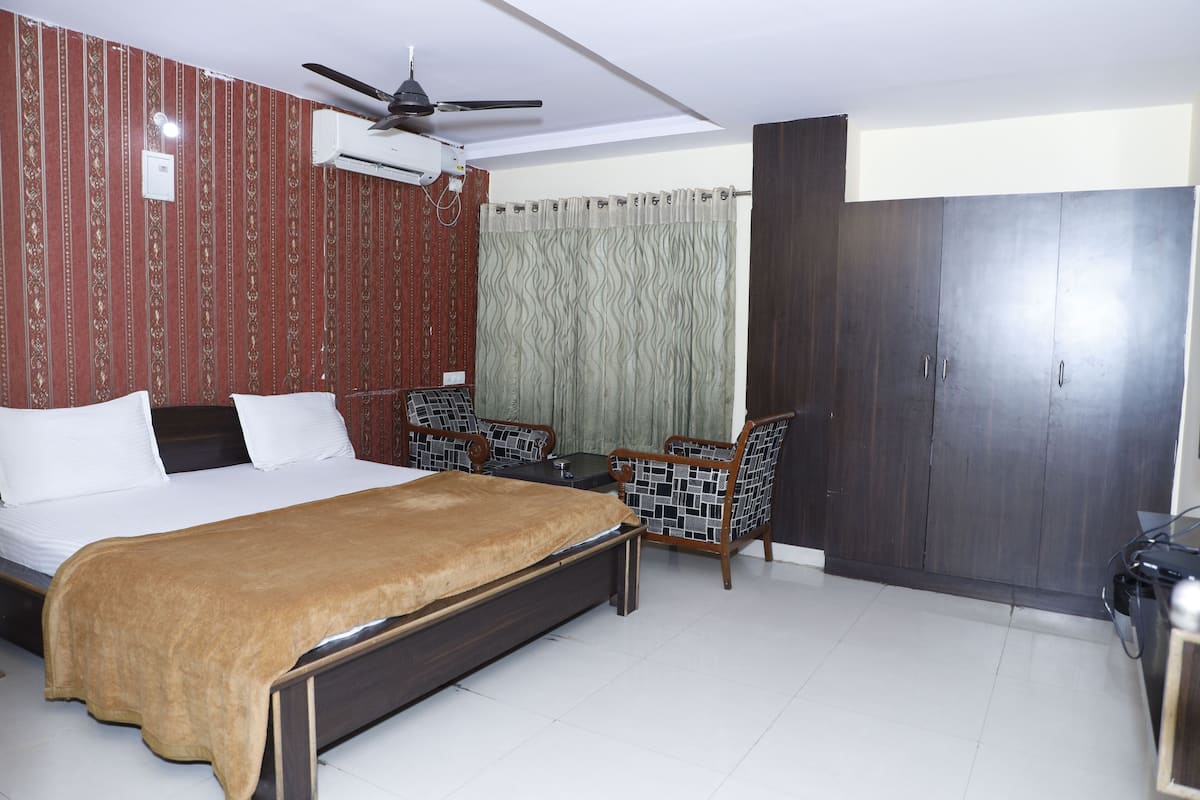 A bedroom with a bed, a desk, a chair, a wardrobe, and a ceiling fan.