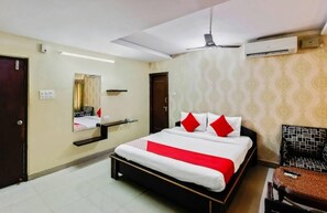A hotel room with a bed, a chair, a mirror, and an air conditioning unit. - Hotel Maruthi Residency Inn (Hyderabad)