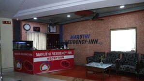 A reception area with a reception desk, seating, a clock, and a wall with the hotel name. - Hotel Maruthi Residency Inn (Hyderabad)