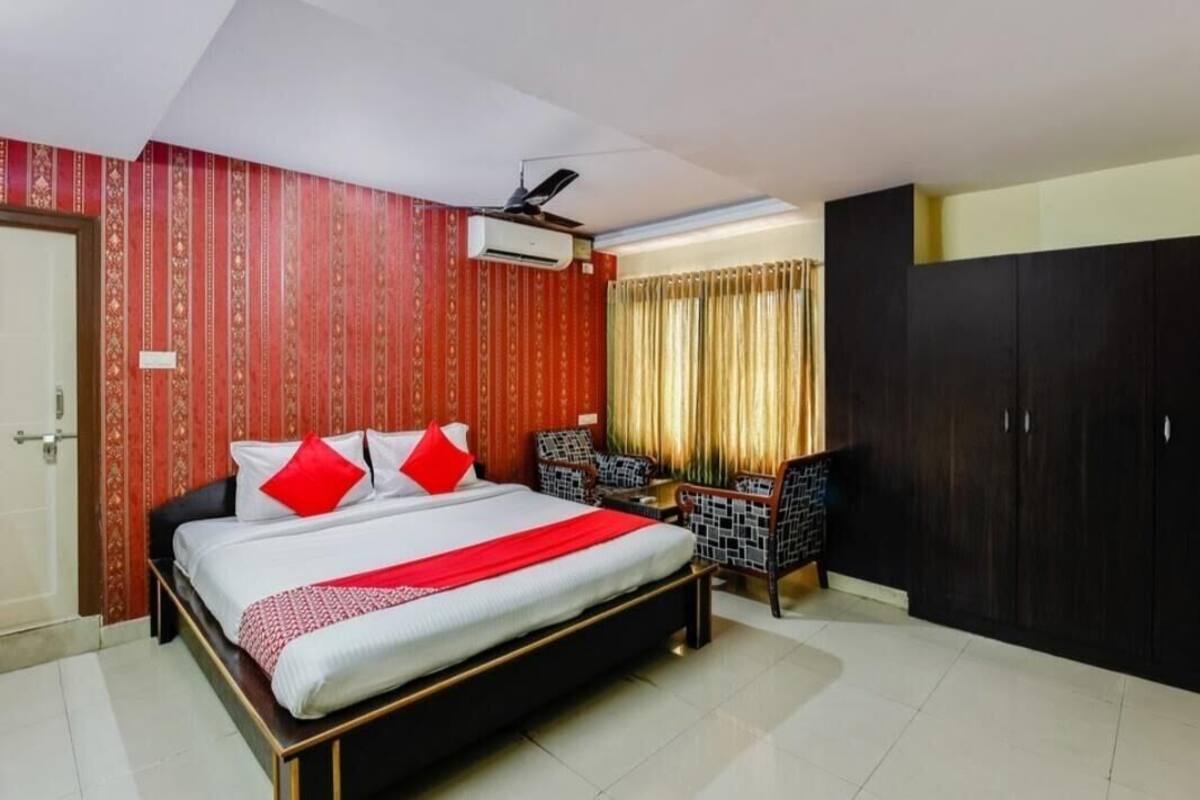 A hotel room with a bed, a desk, a wardrobe, and a window with curtains.
