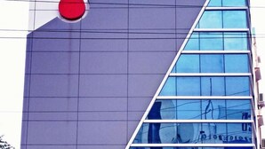 A modern building facade with a prominent red circular feature and a series of reflective glass windows. - Hotel Maruthi Residency Inn (Hyderabad)