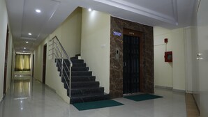 A hotel reception area with a marble wall, a staircase, and a reception desk. - Hotel Maruthi Residency Inn (Hyderabad)