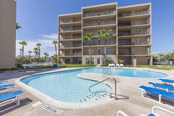 Un hotel a più piani con area piscina, inclusi lettini e un cartello che indica una zona vietata ai tuffi per una profondità di circa 90 centimetri.