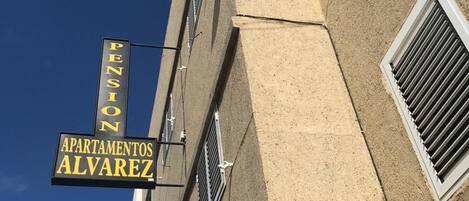 A building with a sign for 'Pension Alvarez Apartments' and a 'Pension' sign on the side.