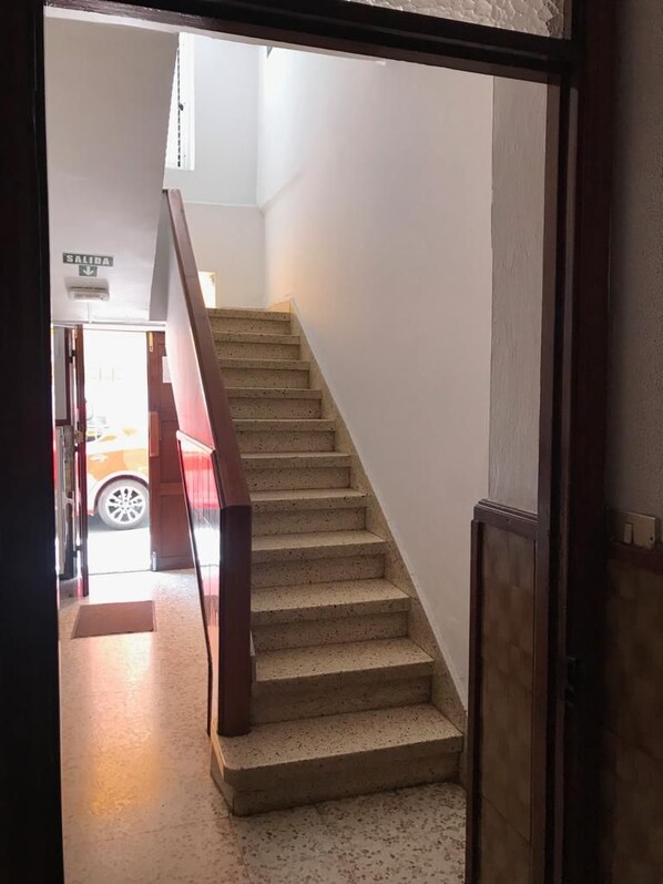 Un escalier menant à l’étage supérieur, avec une main courante sur le côté droit.