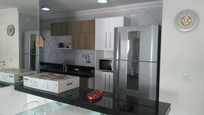 Una cocina moderna con electrodomésticos de acero inoxidable, armarios de madera y encimera negra.
