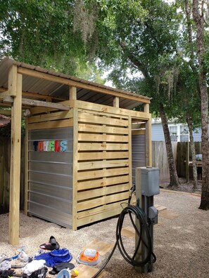 A simple storage shed with a slatted design, housing toilets and a water supply system.