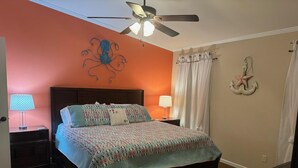 A bedroom with a bed, two bedside tables, a ceiling fan, and decorative wall art. - Steinhatchee Nest House (Steinhatchee)