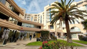 A modern multi-story building with balconies, a central courtyard with palm trees, and a clear sky. - CONFORTABLE T2 AVEC PKG SETE PORT DE PLAISANCE (Sète)