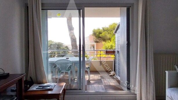 Una habitación con puerta de vidrio corredera que da a un balcón exterior con mesa y sillas.