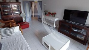 Una sala de estar moderna con sofá, televisor y aparador con puertas de vidrio.