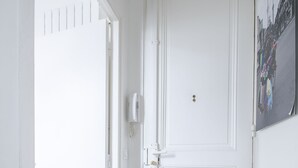 Uma porta branca com design simples, um interruptor de luz e um pequeno prato decorativo na parede.
