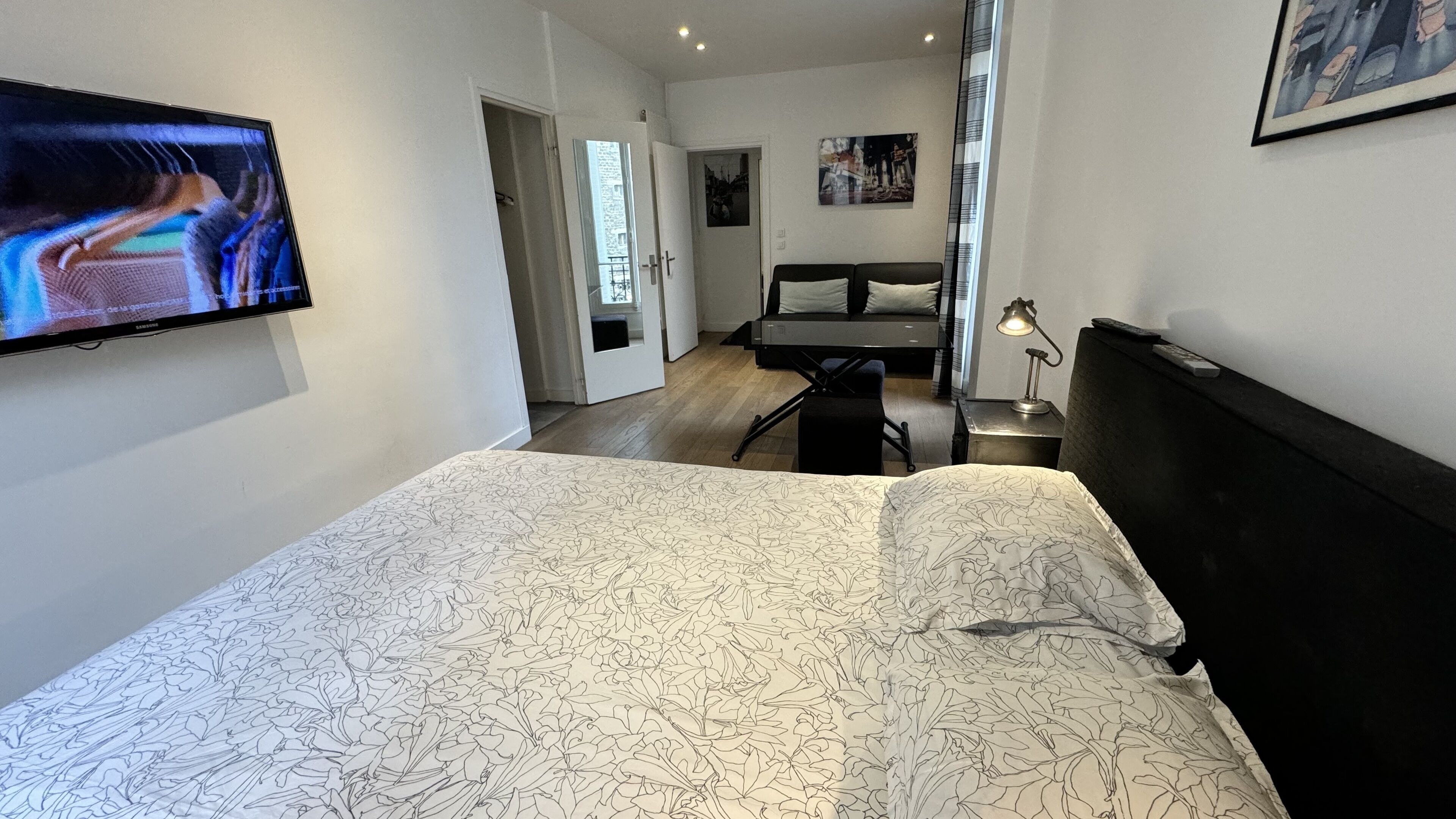 Une chambre à coucher avec un lit, un bureau, une chaise, un téléviseur et un tableau accroché au mur.