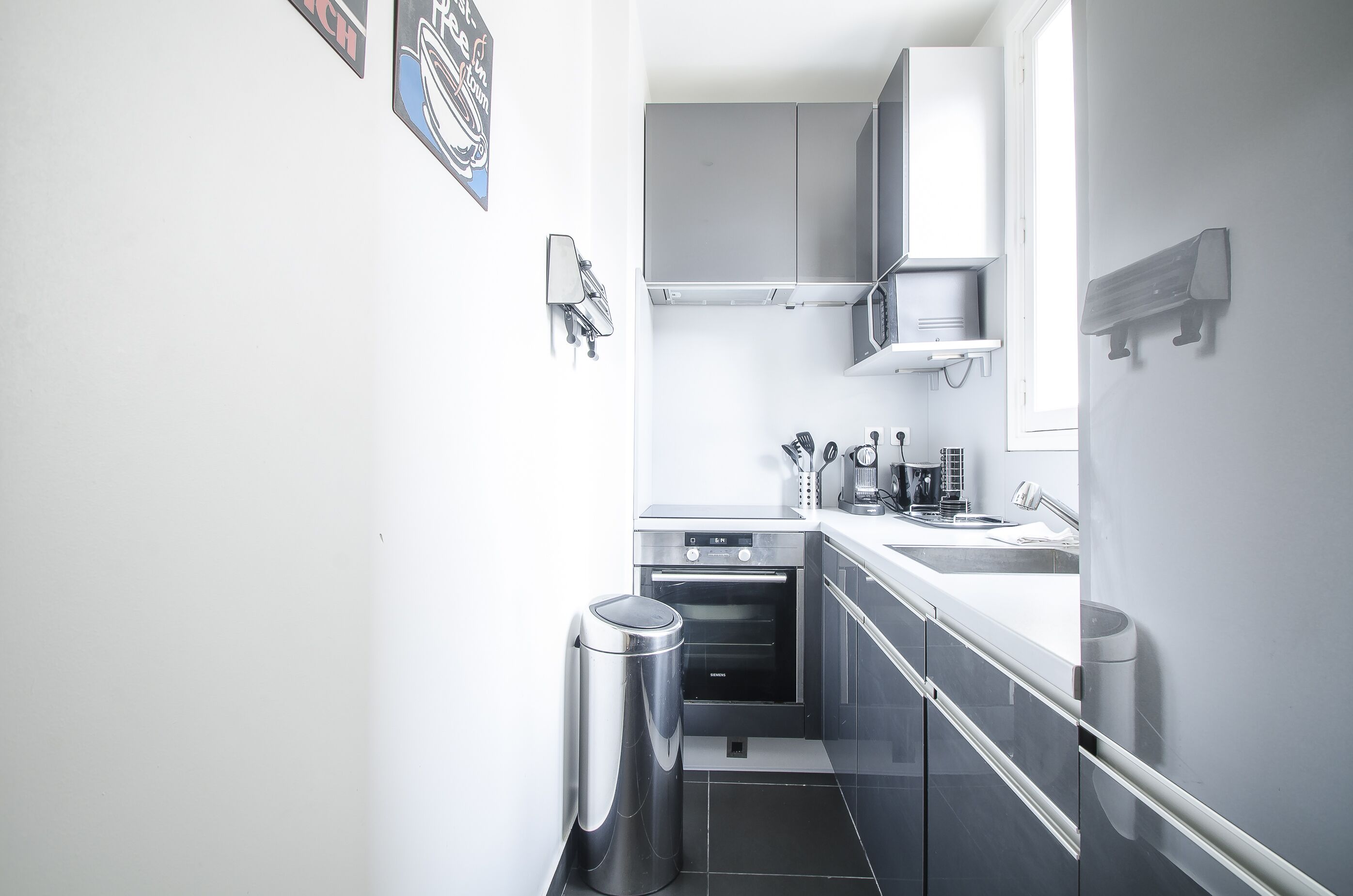 A modern kitchen with a built-in oven, a sink, and stainless steel appliances.