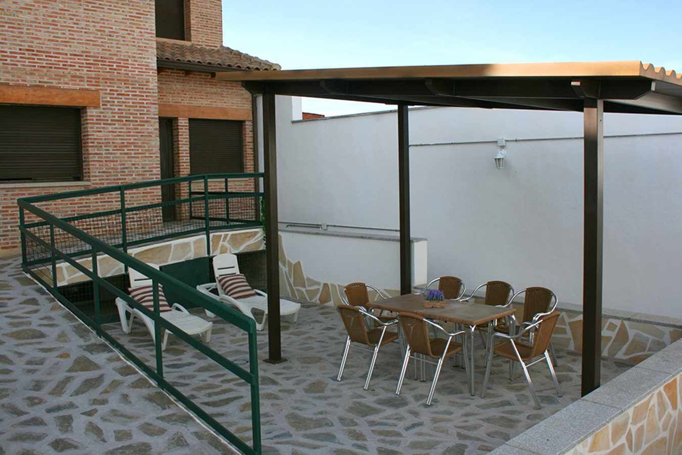 An outdoor patio with a covered seating area, a table, and chairs.