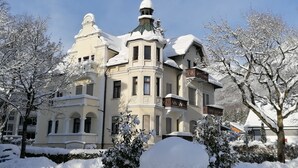 En stor, historisk byggnad med flera balkonger och ett snötäckt tak.