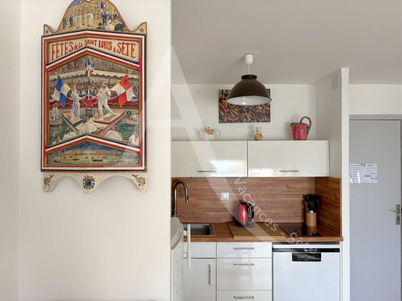 A kitchen with white cabinets, a wooden countertop, a kettle, and a coffee maker.