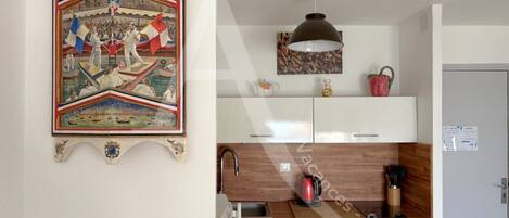 A kitchen with white cabinets, a wooden countertop, a kettle, and a coffee maker.