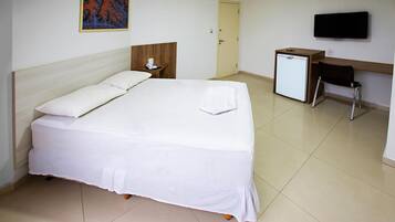 A hotel room with a bed, a desk, a television, and a door.