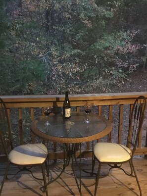 A round table with two chairs, a bottle of wine, and two wine glasses on a balcony with a wooden railing. - Beautiful Custom Cabin on almost 2 acres with lots of privacy (Blue Ridge)