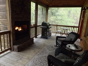 A wooden deck with a stone fireplace, outdoor furniture, and a grill. - Beautiful Custom Cabin on almost 2 acres with lots of privacy (Blue Ridge)
