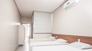 A hotel room with two single beds, a wooden headboard, a white air conditioning unit, and a view of the hallway. - Hotel Imperial Palace (Bom Jesus Da Lapa)