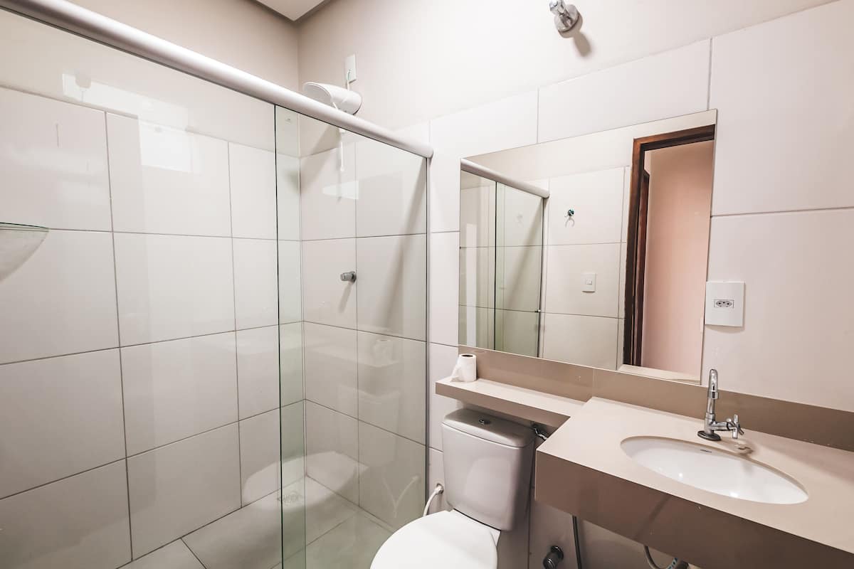 A modern bathroom with a glass shower enclosure, a toilet, and a sink with a mirror above it.