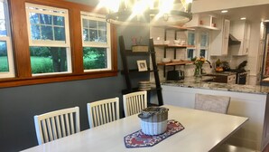 A modern kitchen with white cabinetry, a granite countertop, and a dining area with a white table and chairs. - Beautiful family home (Port Washington)