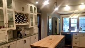 A kitchen with white cabinets, a coffee maker, and a wooden island. - Beautiful family home (Port Washington)