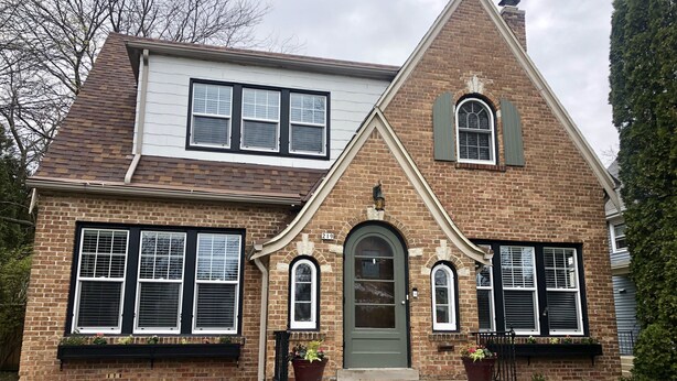 A two-story brick house with a green front door, white shutters, and a small porch with steps. - Beautiful family home (Port Washington)