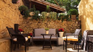 An outdoor patio with stone walls, wicker furniture, and potted plants. - EZKONBERRI VACATION RENTAL (Unzué)