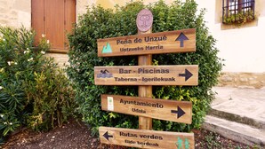 A wooden directional sign with multiple arrows pointing to different destinations. - EZKONBERRI VACATION RENTAL (Unzué)
