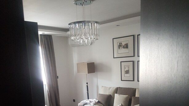 Una sala de estar con sofá, mesa de centro, lámpara y candelabro.