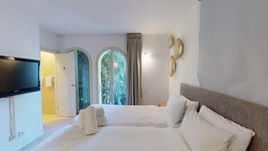 Ein Hotelzimmer mit einem Bett, einem Fernseher und Blick auf Grün durch die Fenster.