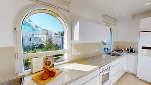 Eine moderne Küche mit großem Fenster, weißen Schränken und einem eingebauten Backofen.
