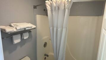 Un baño con cortina de ducha, inodoro y toallero con toallas dobladas.