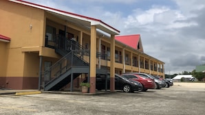 Un motel à plusieurs étages, avec un toit rouge et un parking.