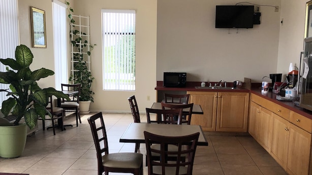 Un coin repas avec une table et des chaises, une cuisine équipée d’un four à micro-ondes et d’une machine à café, et un téléviseur fixé au mur.
