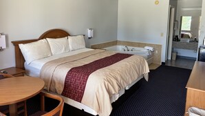 Une chambre d’hôtel avec un lit, une salle de bain dotée d’une baignoire, une table ronde en bois et une chaise.