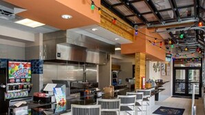 A restaurant interior with a high ceiling, metal chairs, a counter, and a colorful menu board. - Solterra Sunshine - 5* - South facing large pool/spa - game room, gated resort (Davenport)