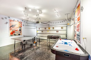 A room with a shuffleboard table, a billiards table, and a table tennis table. There are posters on the walls and a ceiling light fixture. - Solterra Sunshine - extra large pool/spa faces South- views - game room, resort (Davenport)