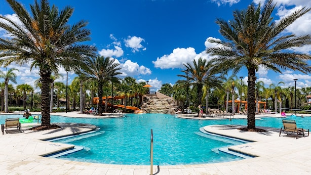 A large outdoor swimming pool surrounded by palm trees, with a water slide and lounge chairs. - Solterra Sunshine - 5* - South facing large pool/spa - game room, gated resort (Davenport)